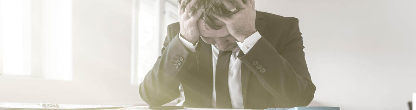 tax_problems man stressed with head resting on hands